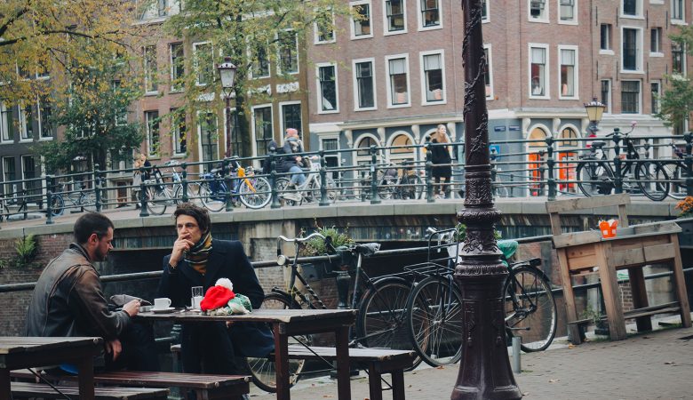 2 men sitting by the canal of Amsterdam